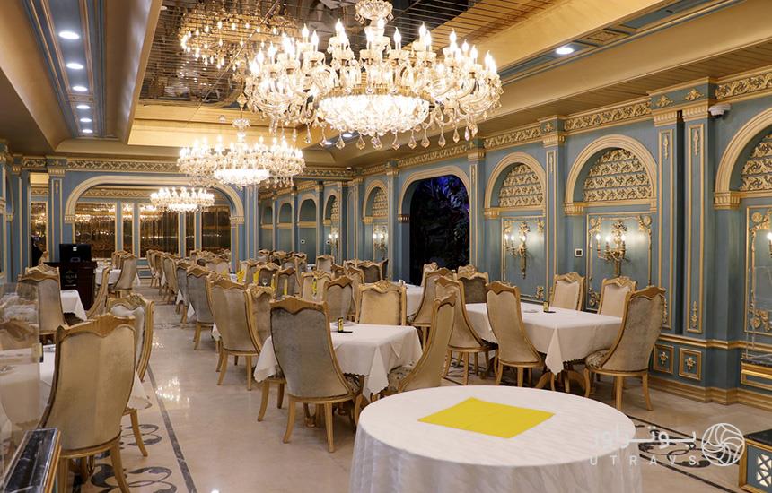 تصویری از رستوران هتل درویشی مشهد، با چلچراغ‌های بزرگ، ترکیب رنگی آبی و طلایی و میز و صندلی‌های کرمی‌رنگ